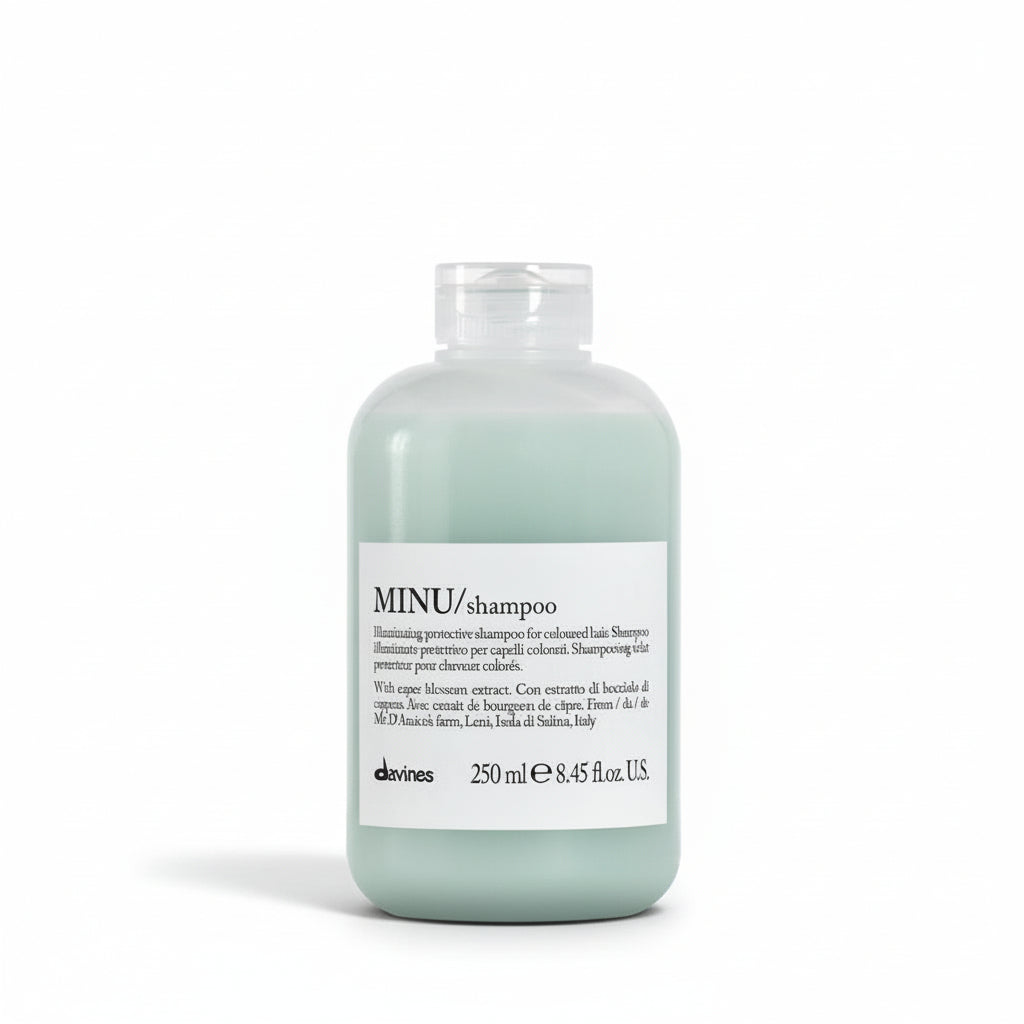 Champú Davines MINU para cabello teñido. Botella azul claro sobre fondo blanco mostrando la textura espumosa y el beneficio de protección del color, Panamá