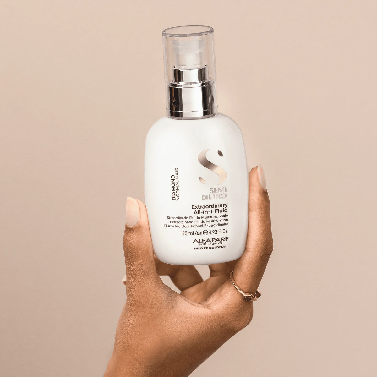 Envase de Alfaparf Semi di Lino Diamond Extraordinary All-in-1 Fluid 125 ml en una mano, tratamiento sin enjuague para suavidad y control del frizz.