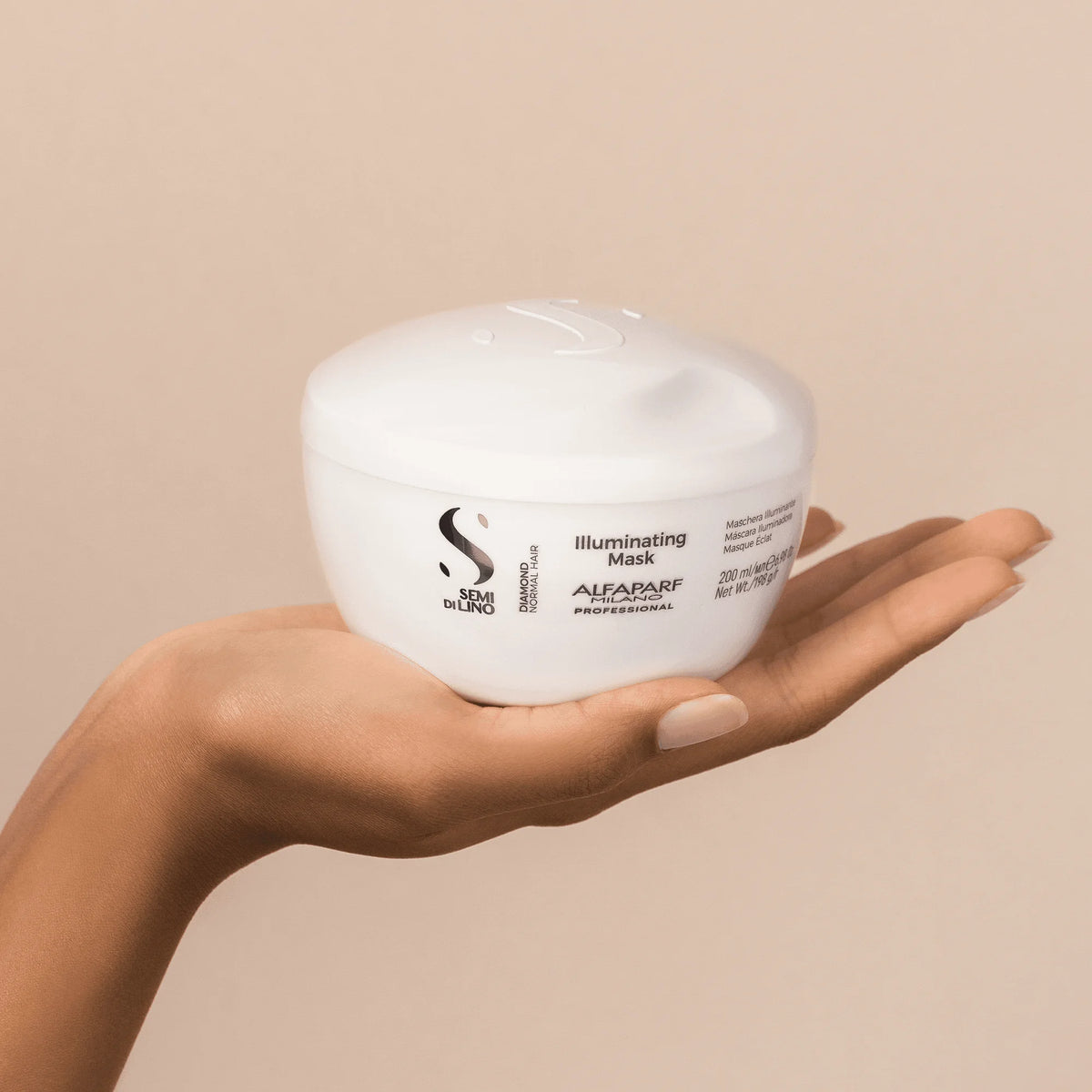 Envase de Alfaparf Semi di Lino Diamond Illuminating Mask 200 ml sobre una mano, tratamiento iluminador para cabello normal.