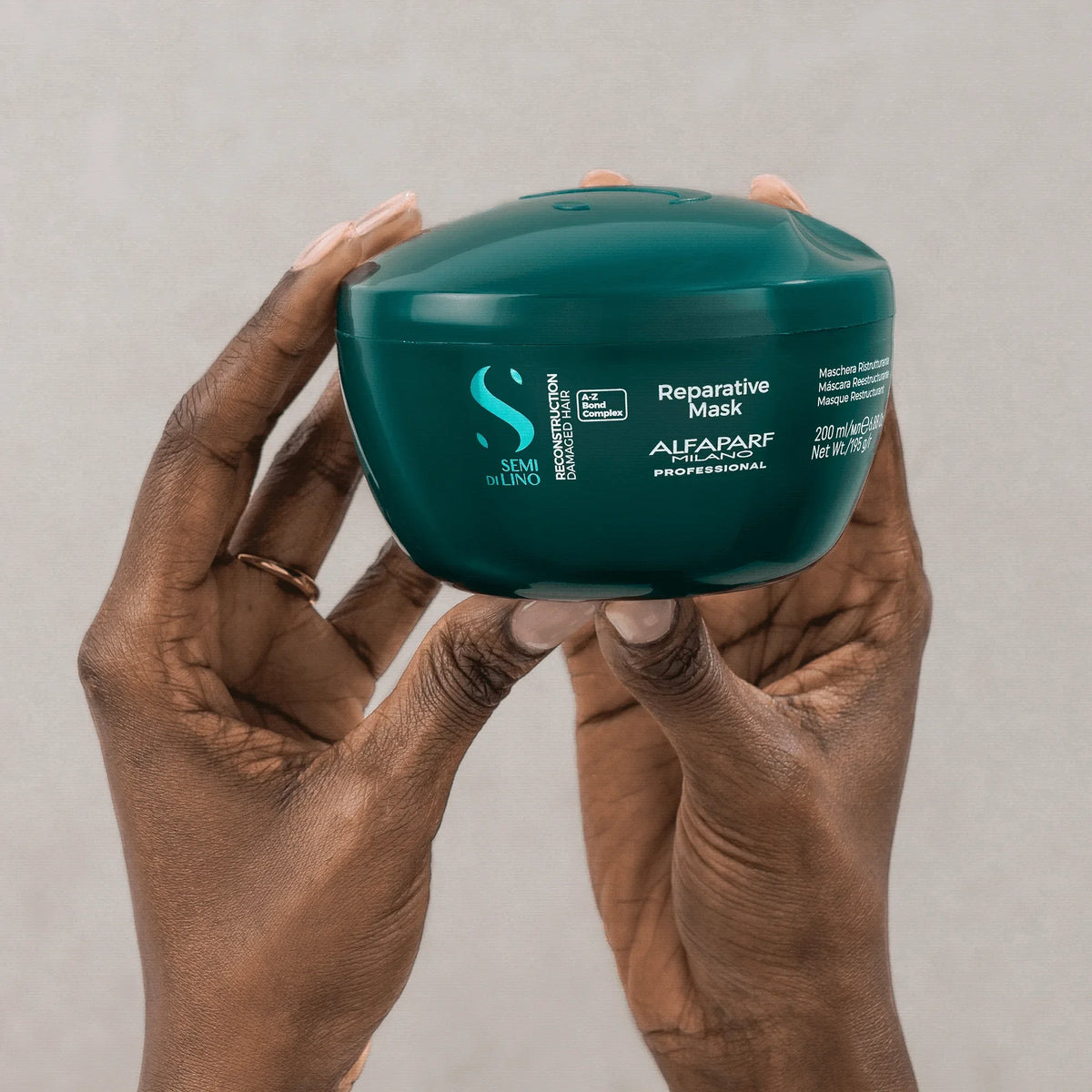 Alfaparf Reparative Mask 200 ml con A-Z Bond Complex, envase sostenido entre las manos.