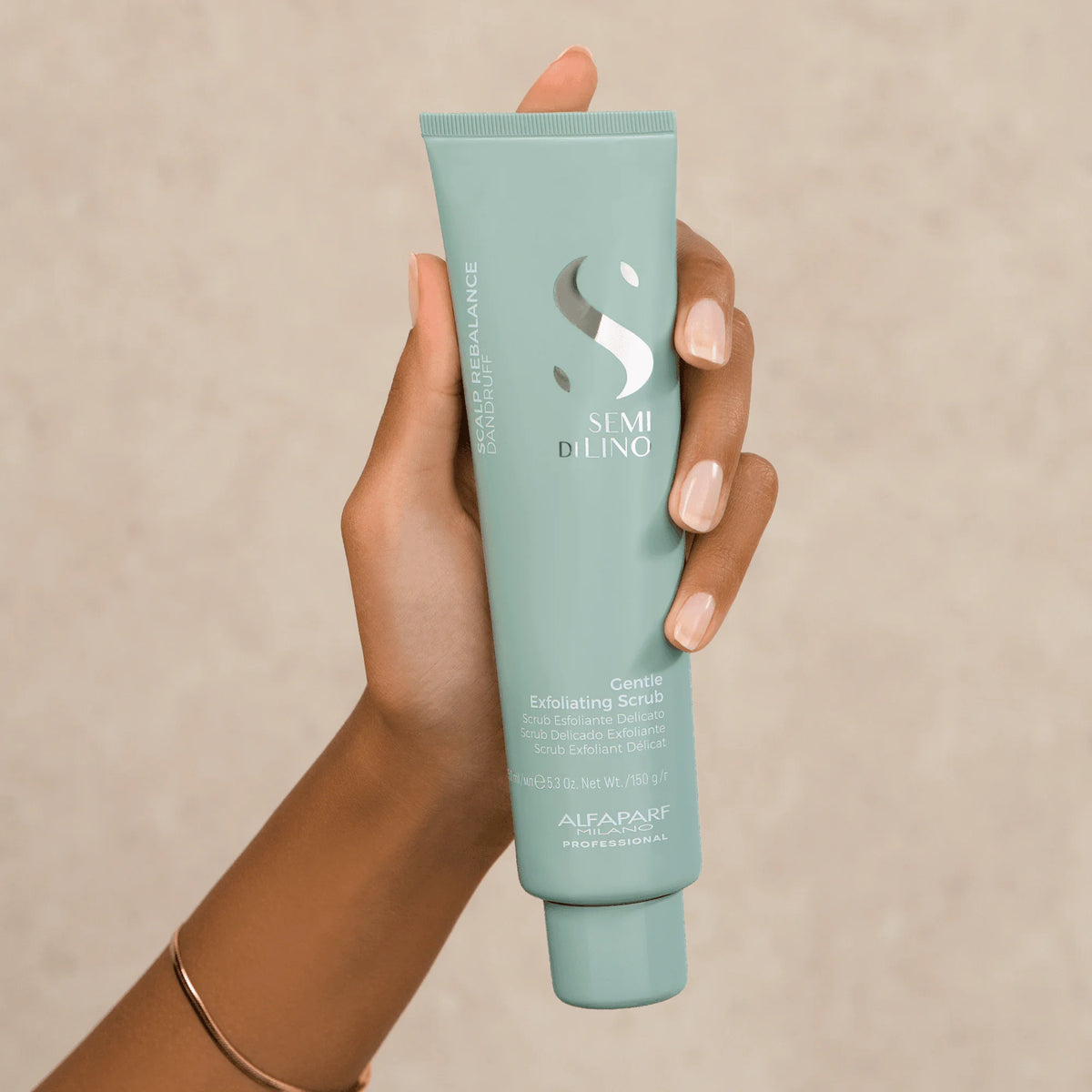 Alfaparf Semi di Lino Gentle Exfoliating Scrub 150 ml sostenido en una mano, exfoliante que ayuda a controlar el exceso de grasa.